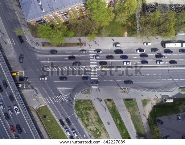 Road junction with a pedestrian crossing. A\
crossroads, traffic of cars and pedestrians is a top view. Green\
plantings by the road. Spring 2017\
Moscow
