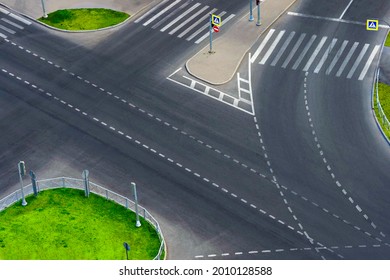Road junction with traffic lights and pedestrian crossings. Cross road, green lawn, traffic island, top view