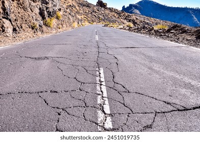 A road with a large crack in it. The road is empty and desolate. The road appears to be in a state of disrepair