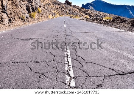 A road with a large crack in it. The road is empty and desolate. The road appears to be in a state of disrepair