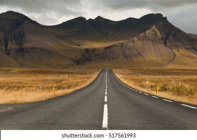 Road leads to a magnificent volcano mountain in the distance, in a dramatic scene in the Snaefellsjokull national park, Iceland.