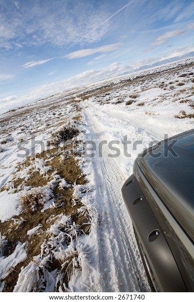 road less traveled - suv exploring a\
remote road in wyoming covered with snow and\
frost
