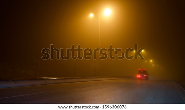 road\
lighting poles and car headlight on a foggy\
night