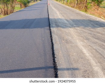 Road Local dual lanes with one half resurfaced with new asphalt tar for vehicle safety improvement.Half old, half new paved road - Shutterstock ID 1924075955