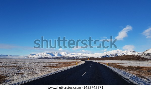 a road lost in Iceland with snowy mountains in\
the background