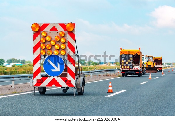 Road maintenance truck and\
signalization for road works, workers repairing\
highway