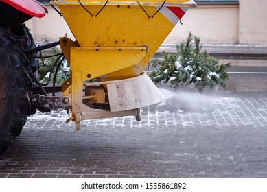 Road maintenance, winter gritter vehicle. Snow plow on pedestrian street salting and cleaning road. Tractor de-icing street, spreading salt on footpath. Municipal service clears street during blizzard