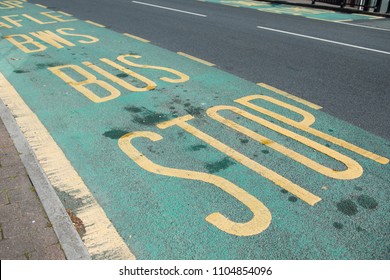 Road Marking. Bus Stop. England. Bus Stop Sign, UK. Yellow Markings On A Green Background.