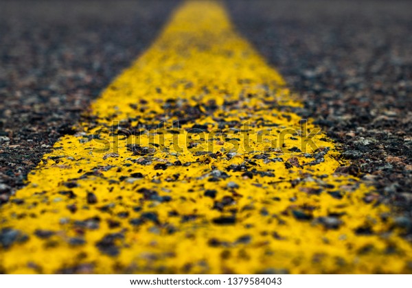 Road marking line with yellow paint on asphalt.\
Marking the motorway.\
Close-up