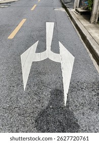 A road marking shows an arrow with split direction, indicating two possible routes and forward direction, it represent anticipation