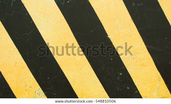 Road markings. Black and yellow stripes on
concrete block texture. Danger on road sign. Serpentine roadside
stop. Danger on highway. Safety driving reminder. Yellow and black
stripes on rough texture