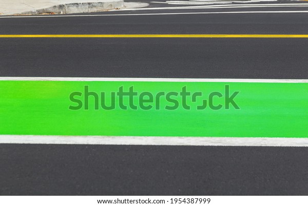 Road markings on gray asphalt, yellow, and bright\
green lines