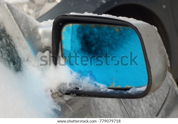 road mirror car\
with a blue tint in the\
snow