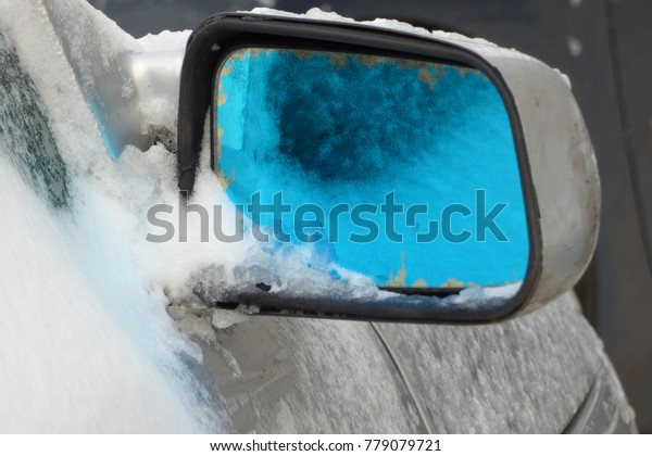 road mirror car\
with a blue tint in the\
snow