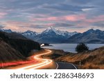 Road to Mt Cook in New Zealand during sunset. Traffic is causing light trails leading to the mountain. 