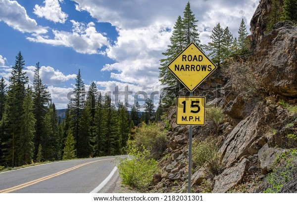 Road Narrows Sign:  A weathered sign warns of\
changing road conditions along the route through Independence Pass\
in central Colorado.\
