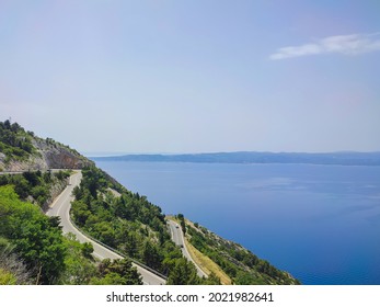 Road On A Mountain Slope By The Sea.Winding Tarmac Road Above Blue Sea.Highway Beside The Sea.Sea Side Street Near The Mountain With Blue Sky In Clear Day.View Of Road. Mountain.Sky.Landscape.