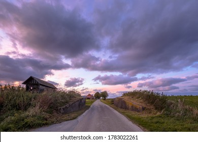 Road passage through dike at sunset under beautiful clouded sky. Usquert, Groningen, Netherlands
