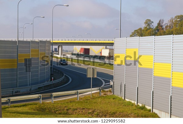 The road is protected against noise emission by\
noise-absorbing barrier (also called a soundwall, noise barrier,\
sound barrier, or acoustical barrier) is an structure designed for\
the protection of people.