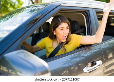 Road Rage. Angry And Aggressive Woman Shouting To A Passing Driver While Arguing During A Traffic Jam