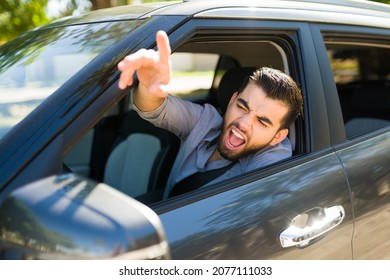 Road rage concept. Angry and aggressive young man shouting to a passing driver while arguing during a traffic jam - Shutterstock ID 2077111033