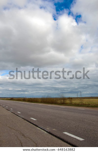 Road\
receding into distance against the cloudy blue sky. Landscape rural\
road calling in the way. Track layout for car easy in the\
countryside. Journey to the horizon of the\
planet.