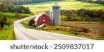 A road, with red barn and silo, through farmland in Upper New York