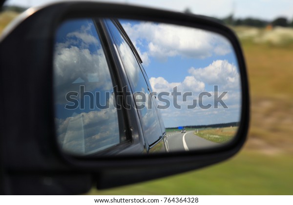 Road\
reflecting in the sideview mirror of a\
car