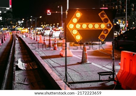 road repair with yellow arrow sign at night 