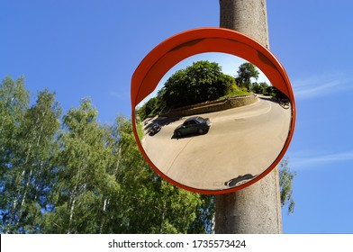 Road round mirror. Mirror to help transport. Help cornering. Red round mirror on a post. Road mirror on a background of blue sky. Give Way.  - Powered by Shutterstock