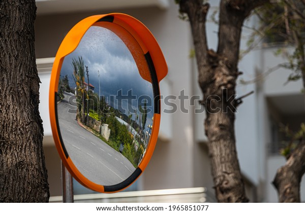 Road round mirror. Mirror to help transport. Help\
cornering. Red round mirror on a post. Road mirror on a background\
of blue sky. Give Way.