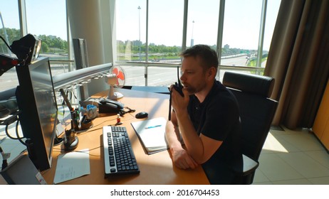 Road Service Employee Using Walkie Talkie And Computer Inside Modern Control Room. Engineer Sitting At Desk And Using Portable Radio In Operating Room.