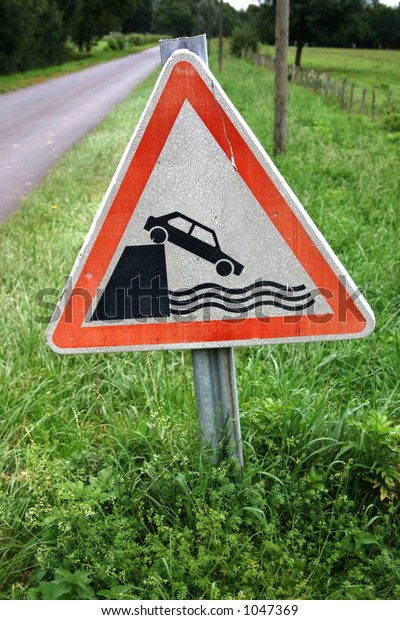 road sign of car falling\
into river