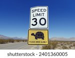 Road sign in a desert area indicating a speed limit of 30 mph warning for desert tortoises potentially crossing the road.