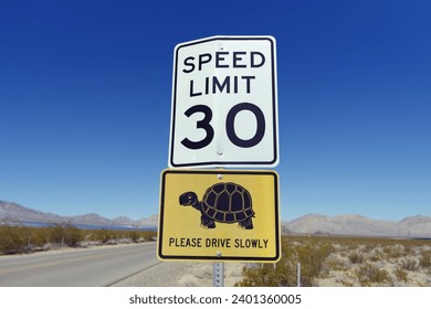 Road sign in a desert area indicating a speed limit of 30 mph warning for desert tortoises potentially crossing the road.
