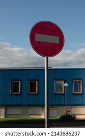 Road Sign Do Not Enter Against The Blue Sky And A Blue Building In The Background On A Sunny Day.