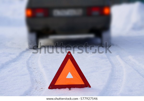 Road sign emergency stop\
of the car (including the emergency lights of the car) on a\
snow-covered road