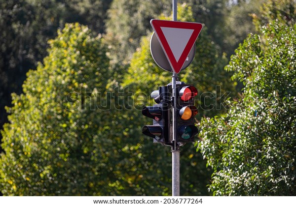 road sign GIVE WAY and\
traffic semaphore with red and orange light against the blurred\
background