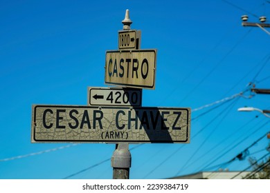 Road sign in the historic districts san francisco california says cesar chavez   castro and white   black paint metal pole  Late in afternoon sun   shade and blue   white gradient sky 