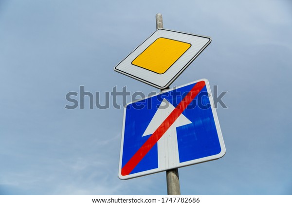 Road sign main road and one-way road end sign\
on blue sky background.