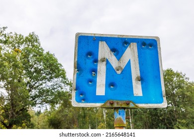 Road sign for a meeting place with bullet holes
