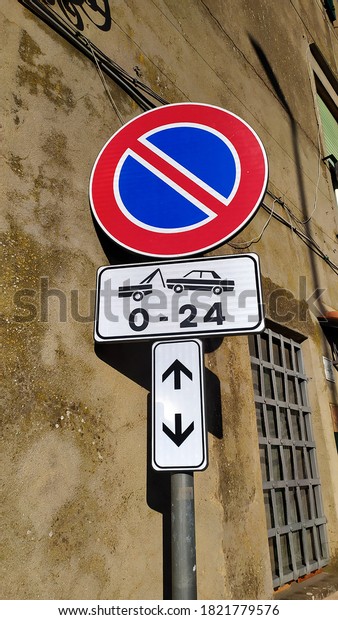 Road sign with no\
parking O - 24, near an ancient building in the sun. conceptual\
image for total ban h24