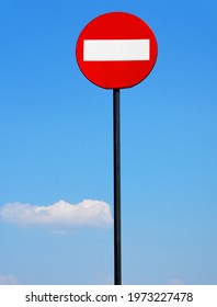 Road sign on a metal pole "Do not enter", with a bottom sign "Wrong way" against a blue sky with clouds