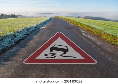 Road Sign On A Street With Attention Slippery When Wet In Spring, Autumn, Fall Or Winter