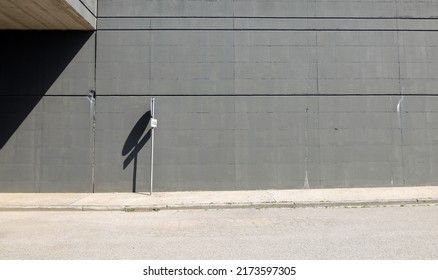 Road sign on white concrete sidewalk. High gray concrete block wall on behind and paved road in front. Background for copy space - Powered by Shutterstock