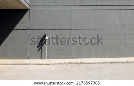 Road sign on white concrete sidewalk. High gray concrete block wall on behind and paved road in front. Background for copy space