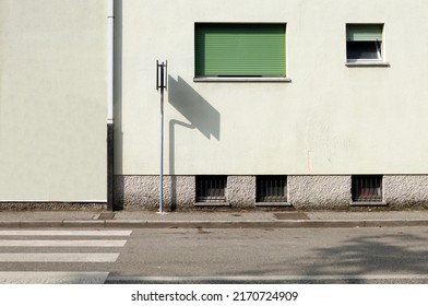 Road sign with shadow on the condominium facade. Paved sidewalk and asphalt street in front. Urban background for copy space - Shutterstock ID 2170724909