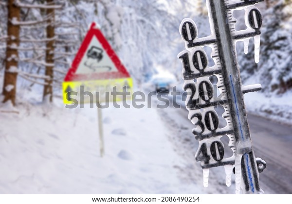 Road sign and thermometer with sub-zero\
temperatures warn of snow, ice and\
slipperiness