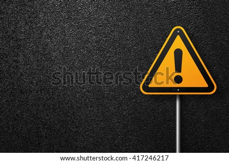 Road sign triangular shape with exclamation mark on a background of asphalt. The texture of the tarmac, top view.