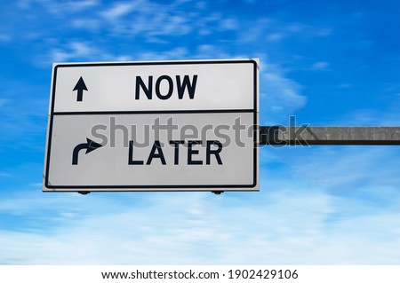 Road sign with words now and later. White two street signs with arrow on metal pole. Directional road, Crossroads Road Sign, Two Arrow. Blue sky background